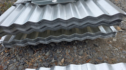 Stack of corrugated metal roofing sheets on a gravel surface