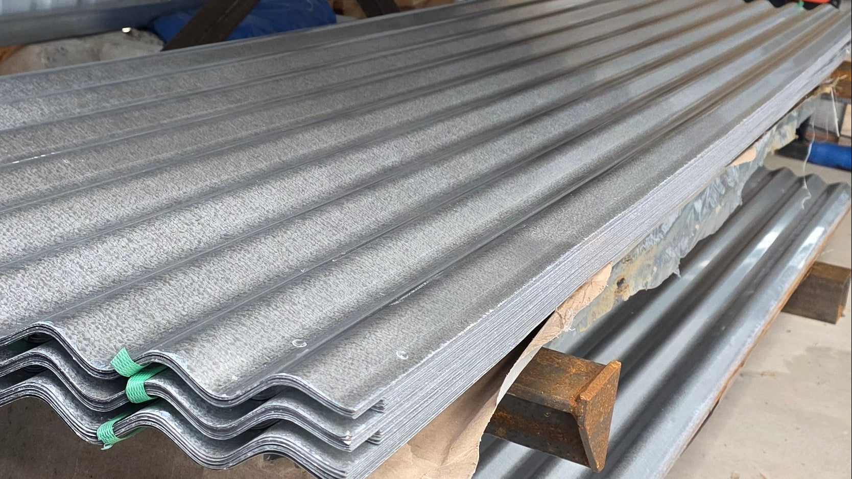 Corrugated metal sheets on a wooden pallet with a concrete wall background